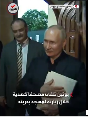 Vladimir Poutine prend dans ses bras un exemplaire du Coran, et exprime son respect aux symboles sacrés des musulmans, jeudi 29 juin à Daghestan.